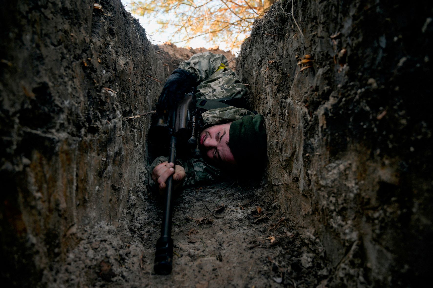 A Ukrainian soldier hides from a helicopter air strike amid Russia's invasion of Ukraine, near Demydiv, Ukraine on March 10, 2022. 